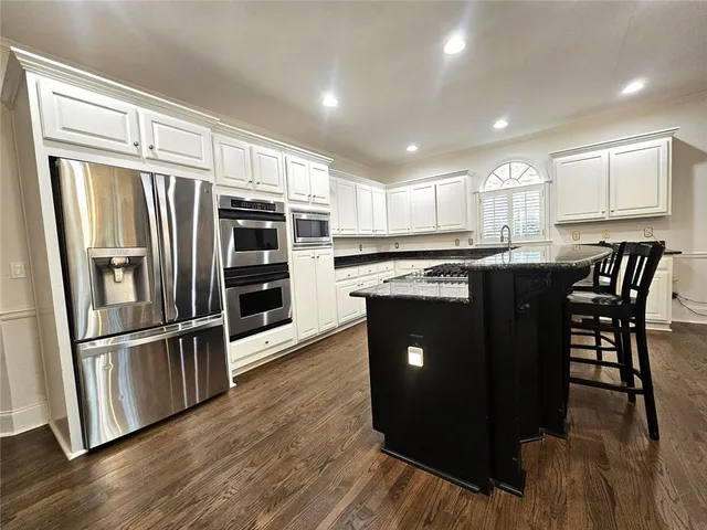 a kitchen with stainless steel appliances granite countertop a refrigerator a stove a sink and a microwave