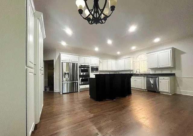 a kitchen with stainless steel appliances kitchen island granite countertop a refrigerator and a sink
