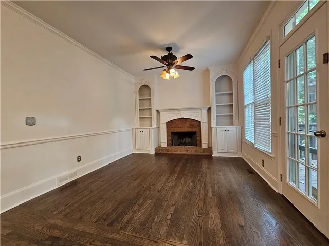 an empty room with windows fireplace and a ceiling fan