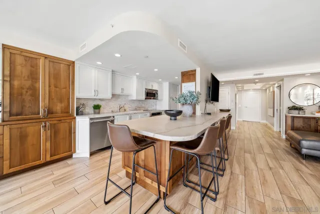 a kitchen with stainless steel appliances kitchen island granite countertop a refrigerator a stove a sink dishwasher and white cabinets with wooden floor