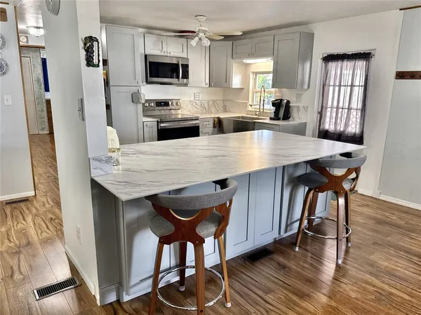 a kitchen with stainless steel appliances granite countertop a table chairs sink refrigerator and microwave