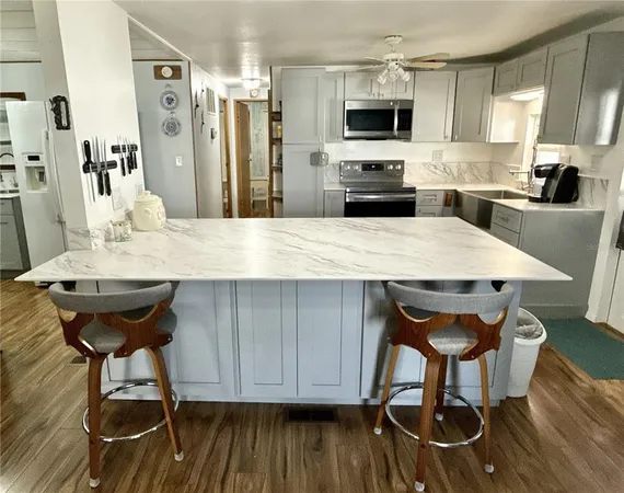 a kitchen with stainless steel appliances kitchen island granite countertop a table chairs and a refrigerator