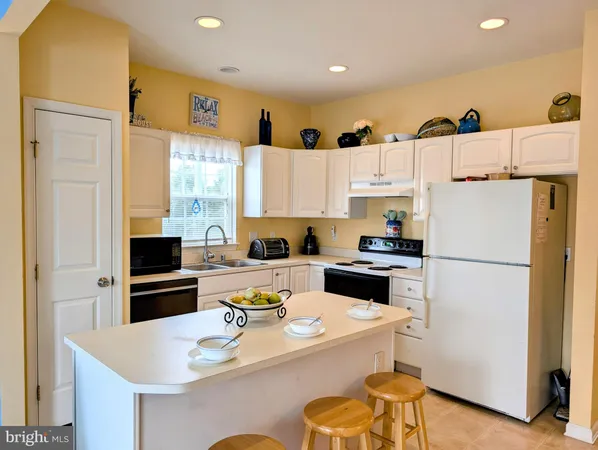 a kitchen with a refrigerator a stove top oven a sink dishwasher and white cabinets with wooden floor