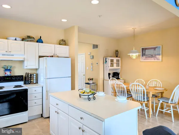 a kitchen with a refrigerator a stove and a dining table with wooden floor