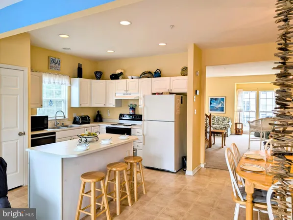 a kitchen with stainless steel appliances kitchen island granite countertop a refrigerator a stove a sink a dining table and chairs with wooden floor
