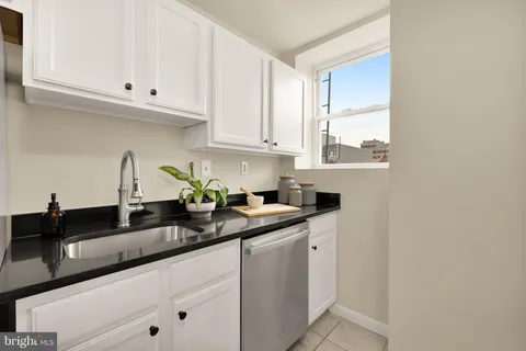 a kitchen with granite countertop white cabinets and a sink