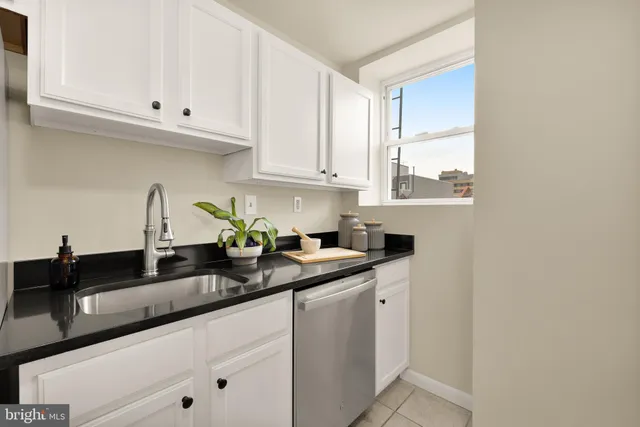 a kitchen with granite countertop white cabinets and a sink