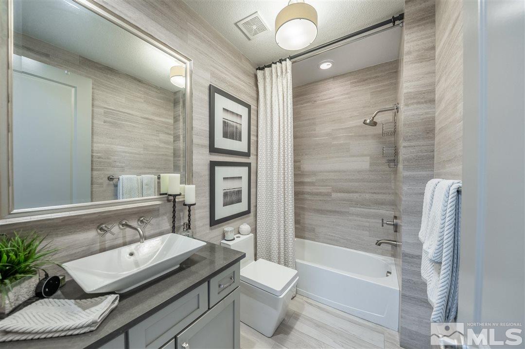9920 Hafflinger Lane Reno, NV 89521 - Photo 23 of 36 a bathroom with a granite countertop sink toilet a mirror and shower