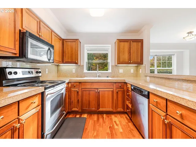 a kitchen with stainless steel appliances granite countertop a stove a sink and a granite counter tops with a large window