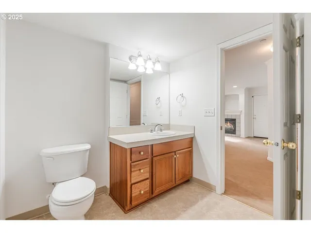 a bathroom with a toilet sink vanity granite and mirror