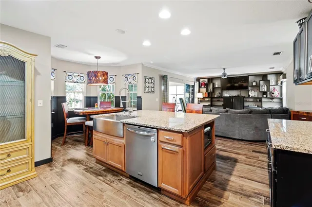 a kitchen with stainless steel appliances granite countertop table chairs and cabinets