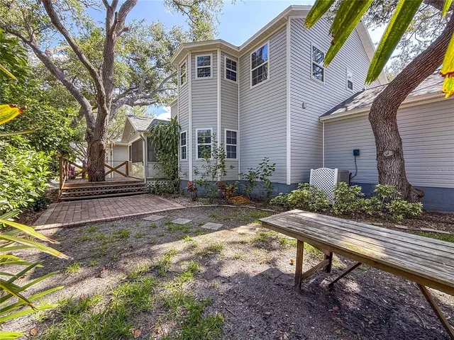 a view of a backyard with potted plants and large trees