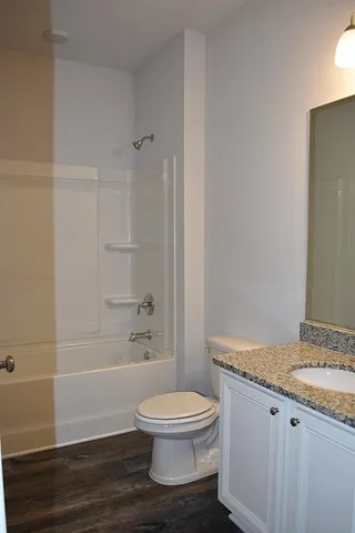 a bathroom with a granite countertop toilet a sink and shower