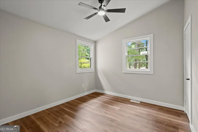 a view of an empty room with a window and wooden floor