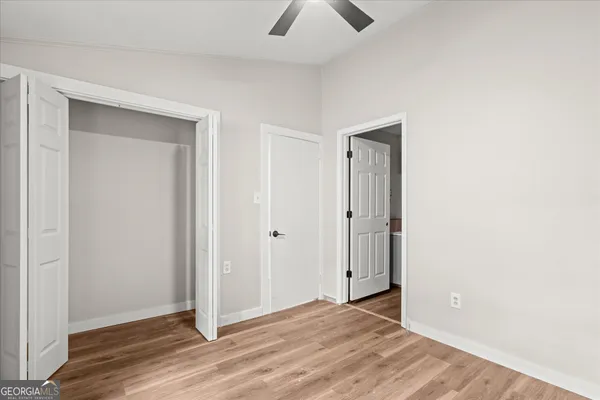 a view of an empty room with wooden floor and closet