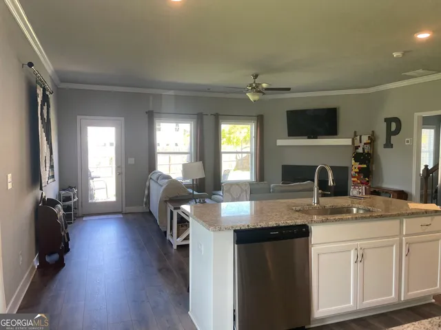 a kitchen with granite countertop a sink cabinets and wooden floor