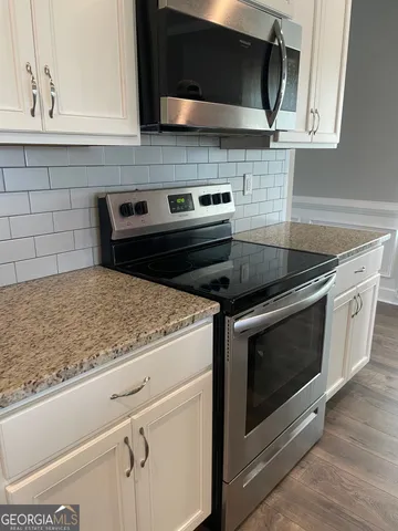 a kitchen with granite countertop a stove microwave and sink