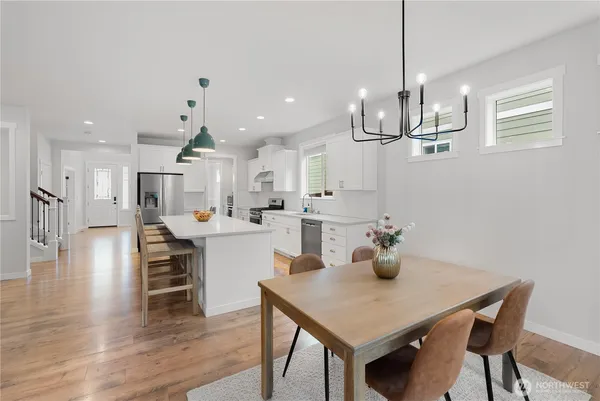 a kitchen with stainless steel appliances a dining table chairs and white cabinets