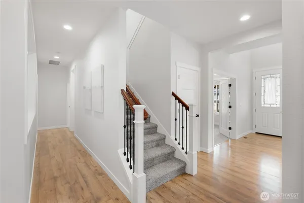 a view of a hallway with wooden floor and stairs