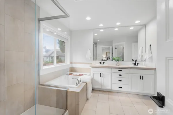 a bathroom with a sink vanity granite tub shower and a mirror