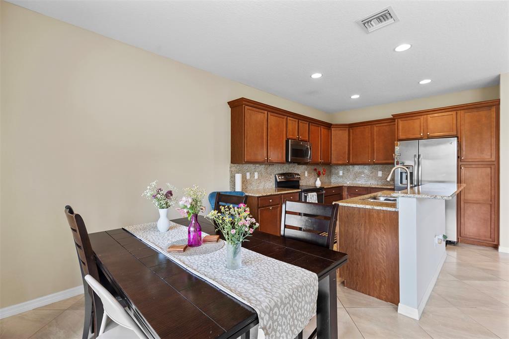 5224 Southwest 77th Way Davie, FL 33328 - Photo 15 of 43 a kitchen with stainless steel appliances granite countertop a refrigerator sink stove dining table and chairs