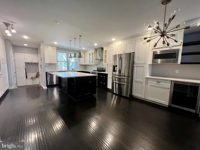 a kitchen with stainless steel appliances kitchen island granite countertop a stove refrigerator and cabinets