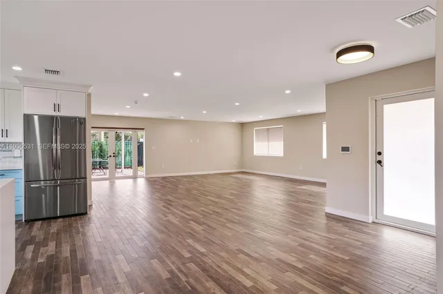 a view of a kitchen with a refrigerator wooden floor and a window