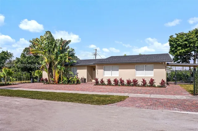a front view of a house with a yard and palm trees