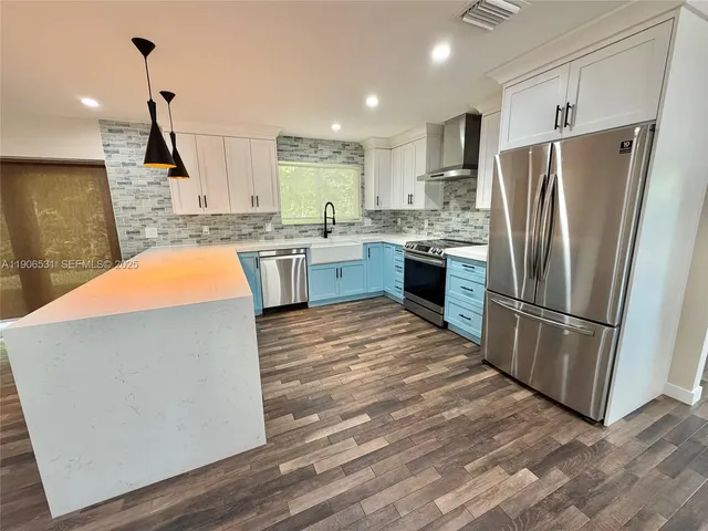 a kitchen with refrigerator a sink and wooden floor