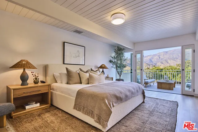 a bedroom with a bed and large windows