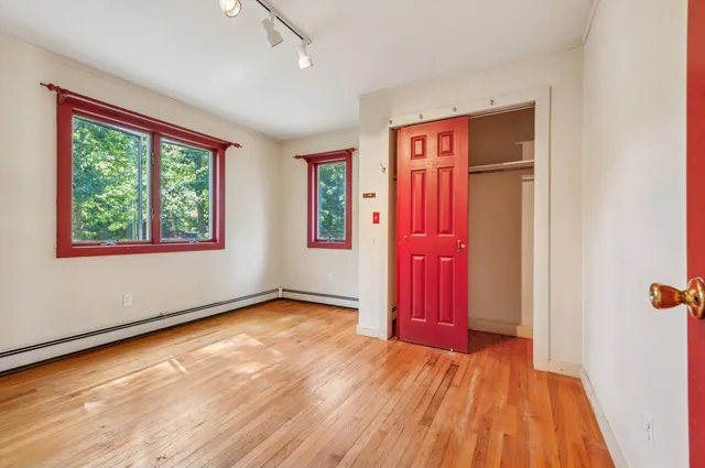 a view of an empty room with wooden floor and a window