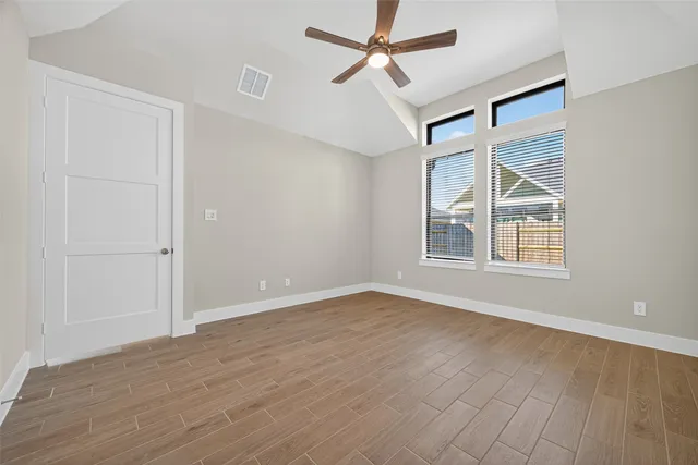 a view of an empty room with a window and wooden floor