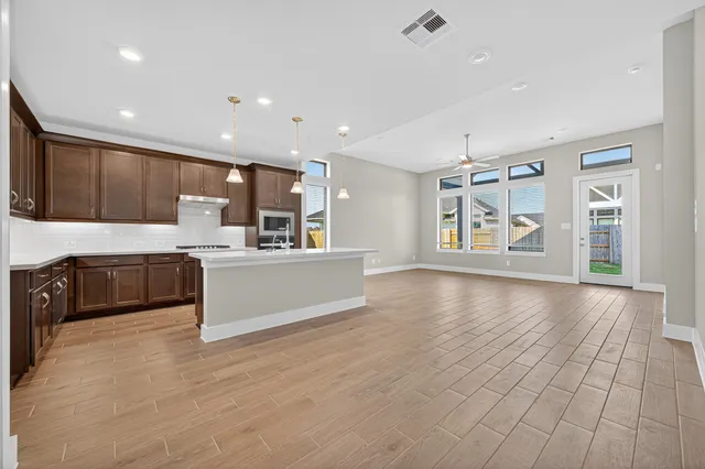 a large kitchen with stainless steel appliances granite countertop a large counter top a wooden floors and a fireplace