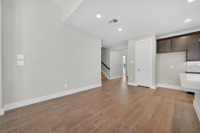 a view of an empty room with wooden floor and a bathroom