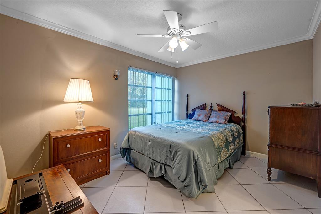 3774 Inverrary Boulevard, Unit 104P Fort Lauderdale, FL 33319 - Photo 13 of 22 a bedroom with a bed and a chandelier