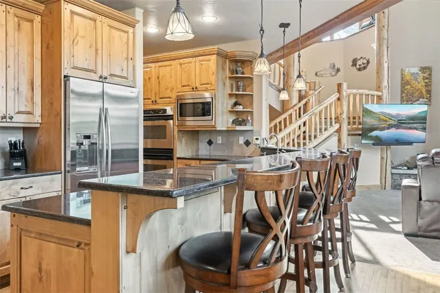 a kitchen with stainless steel appliances granite countertop a dining table chairs and a refrigerator