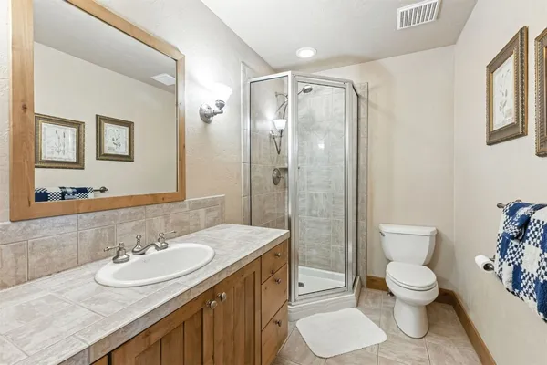 a bathroom with a granite countertop sink toilet a mirror and shower