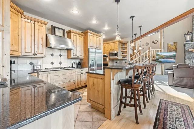 a kitchen with stainless steel appliances kitchen island granite countertop a table chairs sink and cabinets
