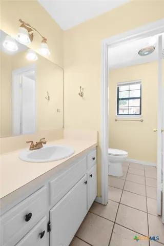 a spacious bathroom with a granite countertop sink a toilet and a mirror