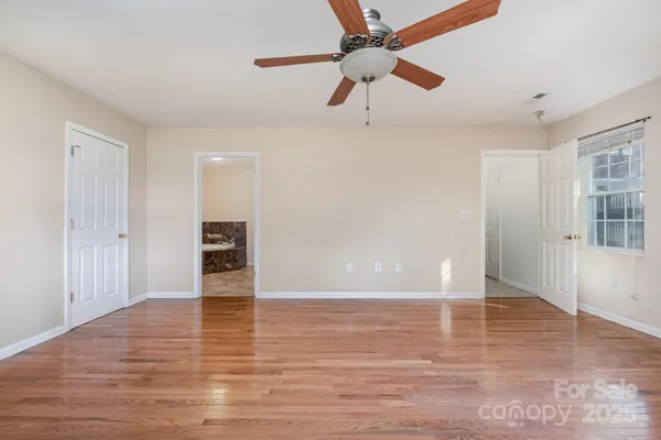 a view of an empty room with window and wooden floor