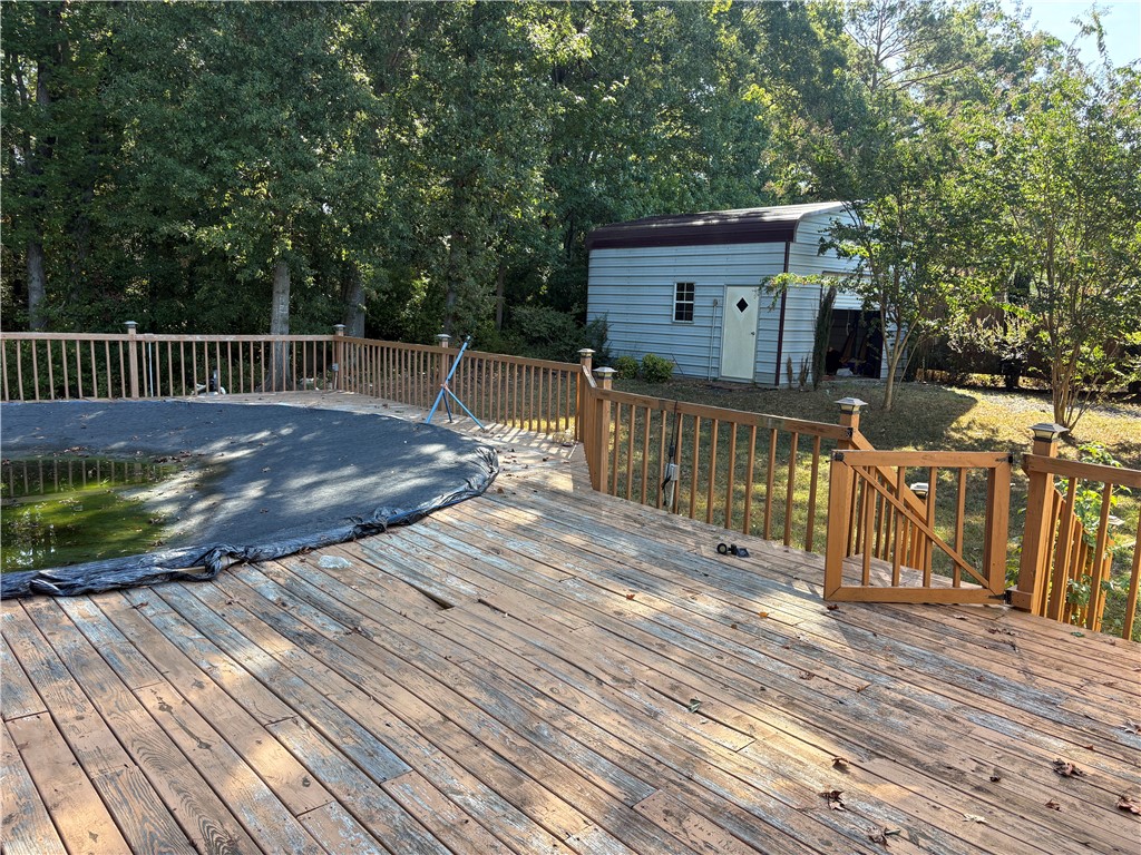 1108 Trotter Road Anderson, SC 29626 - Photo 15 of 27 A spacious wooden deck surrounds the pool area, looking toward a detached storage shed.