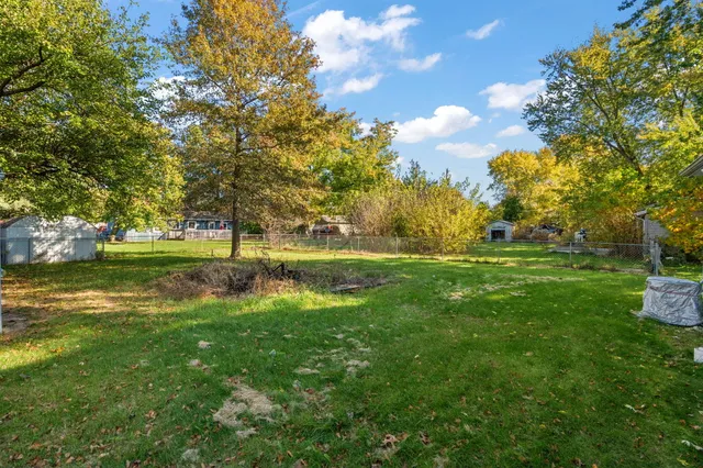a view of grassy field with benches and trees all around