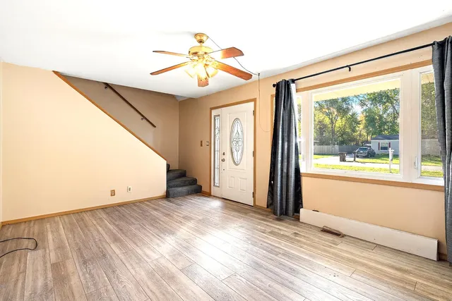 a view of an empty room with wooden floor and a window