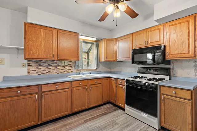 a kitchen with stainless steel appliances granite countertop wooden cabinets stove top oven and sink
