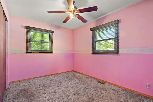 an empty room with a window and a ceiling fan