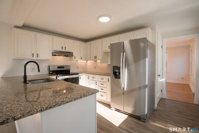 a kitchen with granite countertop a refrigerator and a sink