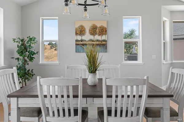 a kitchen with stainless steel appliances a dining table chairs wooden floor and window
