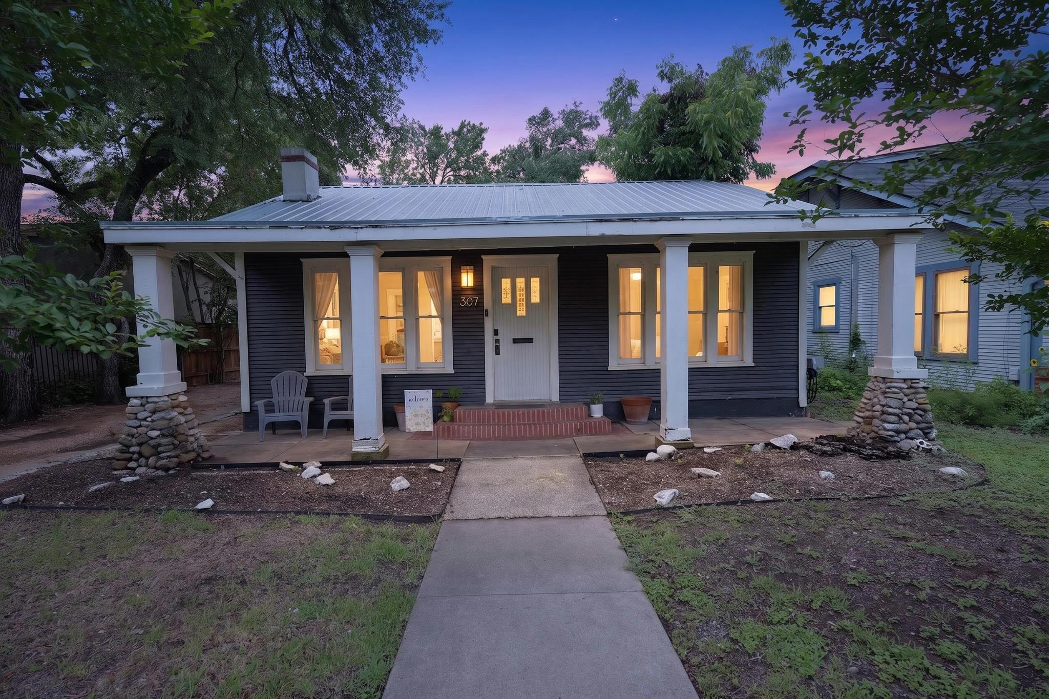 307 East 35th Street, Unit A Austin, TX 78705 - Photo 1 of 40 A charming bungalow with a metal roof and inviting front porch under a twilight sky.