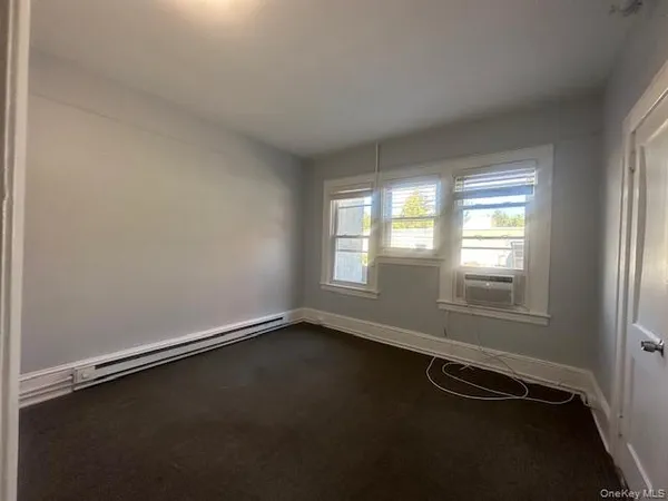 a view of a refrigerator in kitchen and an empty room with wooden floor