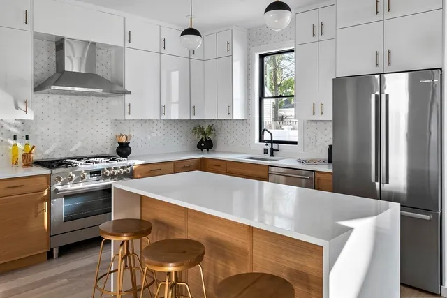 a kitchen with stainless steel appliances granite countertop a sink a stove a refrigerator and island with wooden floor